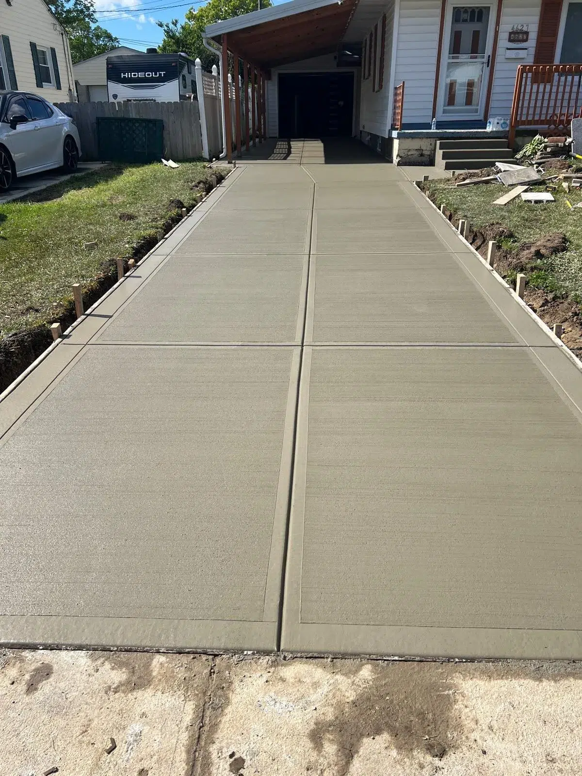 Newly poured concrete driveway with control joints leading to a residential garage.
