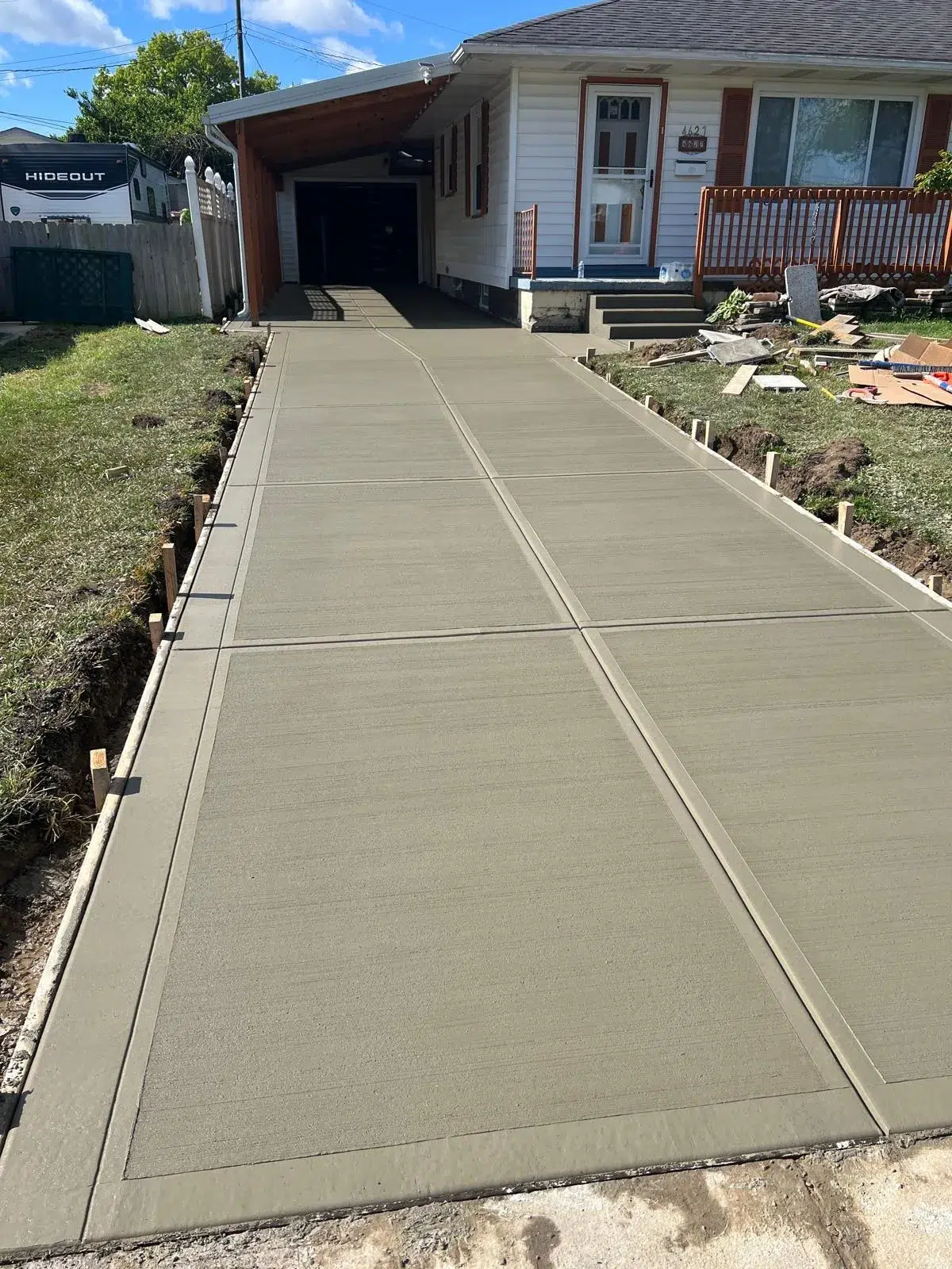 New concrete driveway with control joints leading to an attached carport